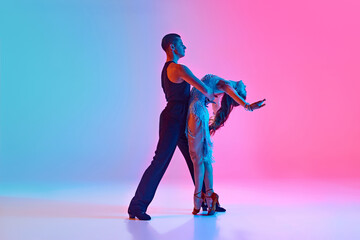Pair of dancers embody art of ballroom dance, perform their refined movements in neon lighting...