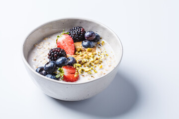 Oatmeal with fresh berries and nuts, white background. Healthy breakfast concept.