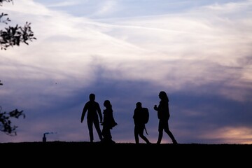 Silhouettes of people walking on the hill