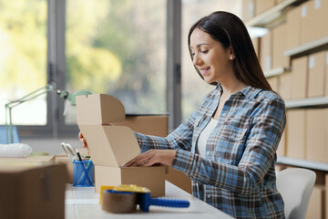 Happy woman putting goods in a delivery box