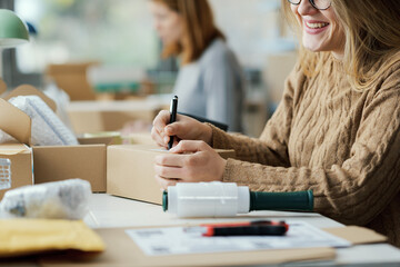 E-commerce employee writing a shipping address on a box