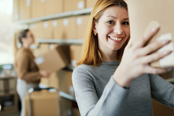 Happy e-commerce employee moving boxes in the warehouse