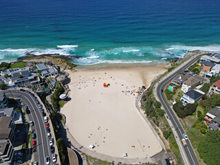 City beach and ocean shore with parked cars, people and houses