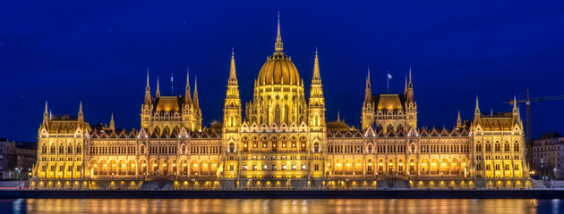 the parliament building lit up at night with clear water and blue sky