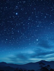 Obraz premium The sky is dark and filled with stars. The stars are scattered throughout the sky, creating a sense of depth and vastness. The mountains in the background add to the sense of grandeur and awe