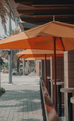 an outdoor patio area with many tables and umbrellas near a brick building