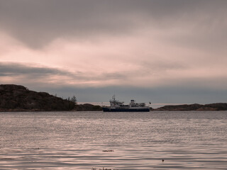 Obraz premium Large boat sailing on a vast body of water close to rocky shores