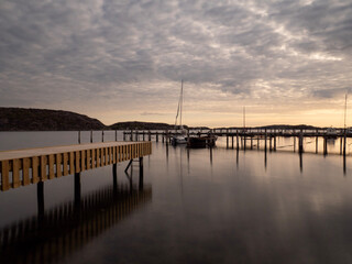 Fototapeta premium Sunset pier reflected in calm waters with a small dock