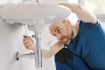 Professional plumber working on a sink
