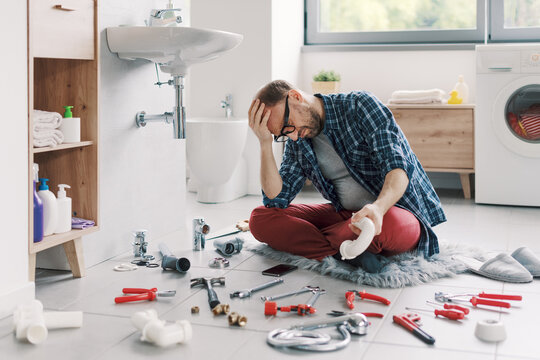 Confused man trying to fix the bathroom sink by himself