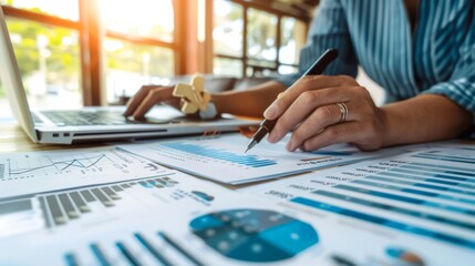 A person analyzing a financial report on a laptop, with graphs and data sheets spread out on the table.