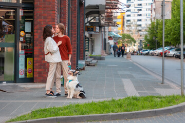 Young couple, man and woman flirting at the street. Family walking together in city with Aussie...