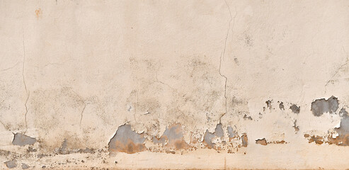 Dirty peeling cracked paint concrete wall. uneven render cement wall with red soil stains. Grunge...