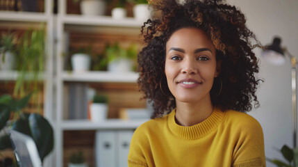 Fototapeta premium Confident woman smiling in home office. Portrait of a happy young woman with natural hair smiling while working from her home office
