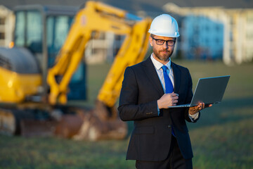 Architect at a construction site. Architect man in suit and helmet at construction site. Confident architect standing at construction. Investor or civil engineer. Outdoor portrait of hispanic