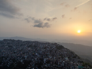 View of the sun set behind a city on the hills