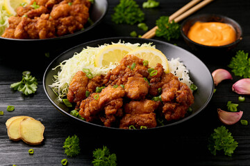 Japanese Fried crispy Chicken Karaage in black bowl with rice and cabbage