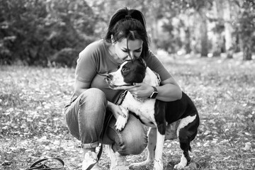 Pretty woman kissing her dog in the autumn park.