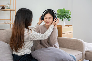 Asian lesbian couple enjoying music together at home. Concept of love, bonding, and leisure in a...