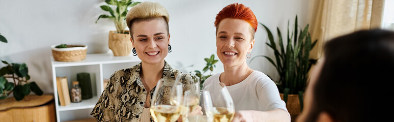 Two diverse women enjoy wine at a table with friends.