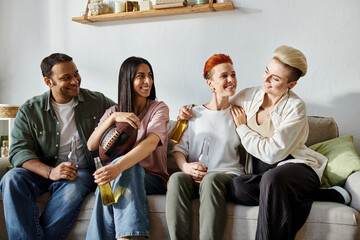 Diverse friends and a loving lesbian couple enjoy each others company on a comfy couch.