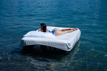 Back of woman resting on a mattress in the water. Water mattress concept. Sweet dreams. Summer...