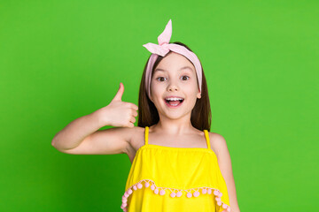 Photo of girlish excited little lady dressed yellow outfit showing thumb up empty space isolated...