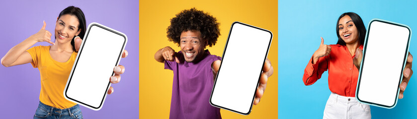 Cheerful multiethnic millennials standing together, holding a phone with a blank screen. They...