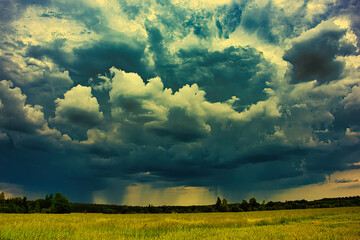 Rozległa równina pokryta młodym, zielonym zbożem. Niebo jest pokryte ciemnymi, skłębionymi chmurami, przez które miejscami przenika światło słoneczne. © boguslavus