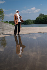A young woman wearing a hijab stands next to a large puddle. 