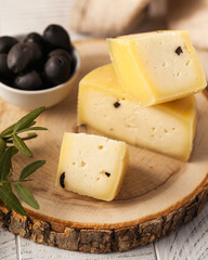 Stacked Caciotta cheese with black olives in the background