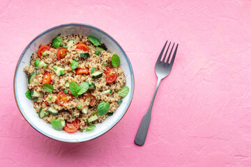 Quinoa tabbouleh salad in a bowl, a healthy dinner with tomatoes and mint, shot from the top with copy space