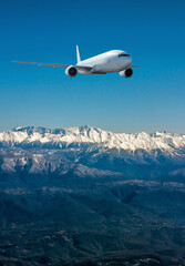 A white wide body jet plane flies over resort mountain town