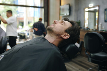 Man resting in styling chair waiting for barber