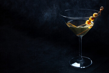 Martini. A glass of dirty martini cocktail with vermouth and olives, on a black background with a place for text