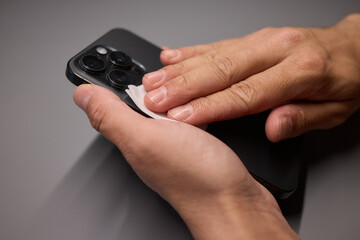 A person is wiping a cell phone clean with a tissue