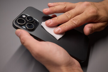 A person is wiping a cell phone clean with a tissue