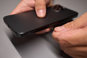 A person is inserting a sim card into a cell phone using hand and fingers