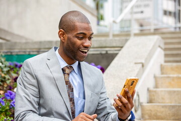 businessman feeling excited and happy while using his mobile phone, reading good news 