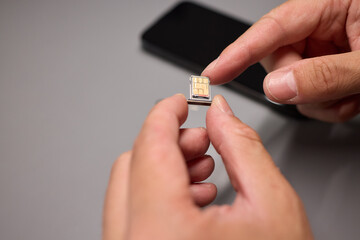 A person is inserting a sim card into a cell phone using hand and fingers