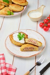 Potato pancakes stuffed with minced meat on a ceramic plate on a light wooden background. Served with sour cream. Belarusian cuisine.