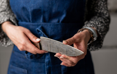 Woman Checks Knife Sharpness In Kitchen Apron, Close-Up Of Hand In Focus