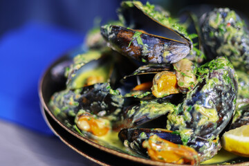 Traditional Mediterranean dish - mussels a la marinier, boiled black mussels with herbs, green leek, garlic, olive oil and toasts. Healthy diet dish cooked in big black stew pan.