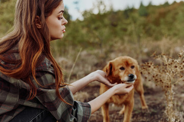Woman bonding with a dog in a serene countryside setting with lush forest background, connection,...