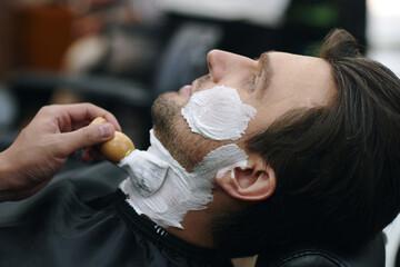 Barber using cream when shaving neckline of client