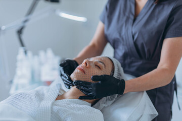 Young pretty woman receiving treatments in beauty salons. Using a face mask