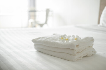 A hotel maid stacked towels on the bed and placed flowers on the towels in a hotel room