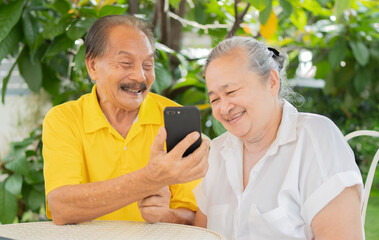 Couple of two old and mature people at home using phone together in the garden. Happy family...