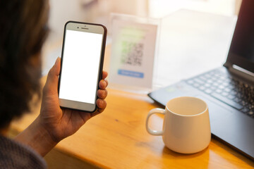 Unrecognizable man's hands on cafe or coffee shop desk, working and using the smart phone with isolate screen.