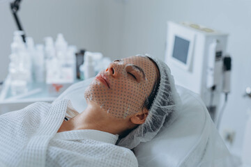 Young pretty woman receiving treatments in beauty salons. Using a face mask